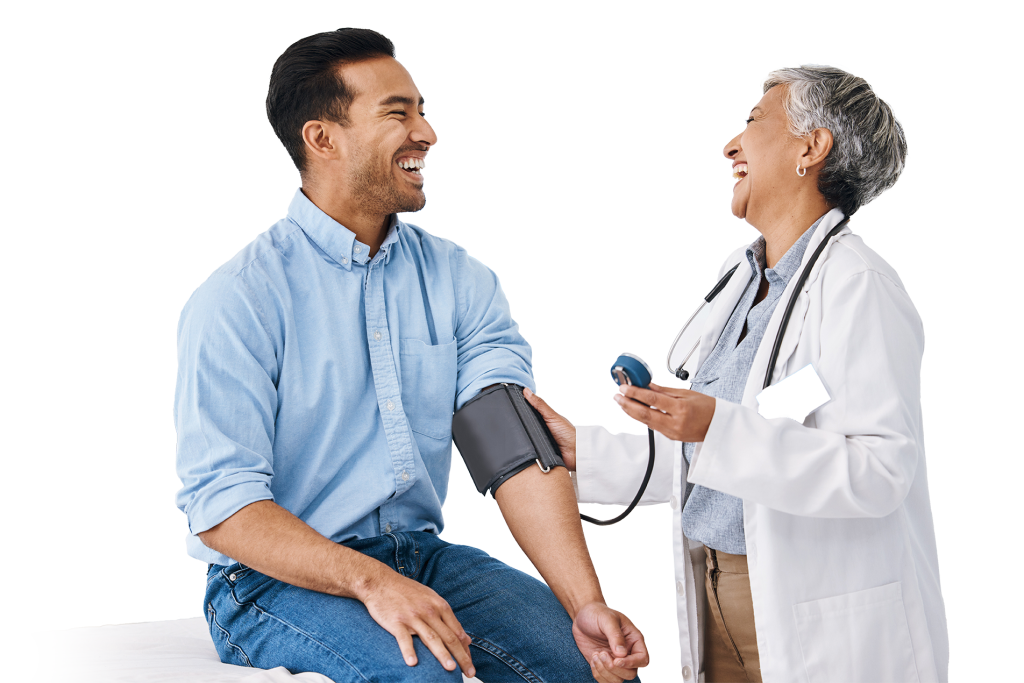 A doctor laughs while taking a seated patient's blood pressure. The patient, smiling in a light blue shirt and jeans, exudes wellness. The doctor, wearing a white coat with a stethoscope around their neck, radiates professionalism. In the background, a poster reads "FLU" in blue letters.